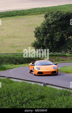 Orange Lamborghini Murcielago Kurvenfahrt und schnelles Fahren in der englischen Landschaft Stockfoto