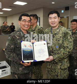 171221-N-TB 148-012 BUSAN, Republik Korea (31. 21, 2017) Republik Korea (ROK) Navy Vice Adm. Jung, Jin-Sup, Commander, ROK-Flotte, präsentiert Leutnant John Lee mit einem Brief der Termin für seine Auswahl an den "großen Jungen Köpfe "Junior Officers' Engagement und Zusammenarbeit. Die Initiative "grossen Jungen Köpfe' vereint hand-selektierte, junge Offiziere von der ROK und der US-Marine und sie vor die Aufgabe, innovative Lösungen für das ROK-US-Allianz der Zukunft weiter entwickeln. (U.S. Marine Foto von Mass Communication Specialist Seaman William Carlisle) Stockfoto