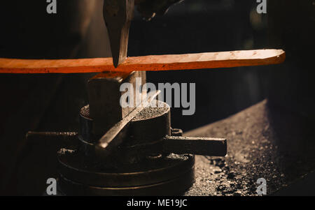 Schlosser schlägt das heiße Bügeleisen um die gewünschte Form zu geben. Stockfoto