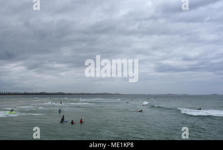 Menschen surfen auf Kingscliff Beach an einem bewölkten Tag. Stockfoto