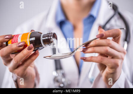 Die Hände der jungen Frau Doktor gießen Arzneimittel Sirup auf Löffel. Stockfoto