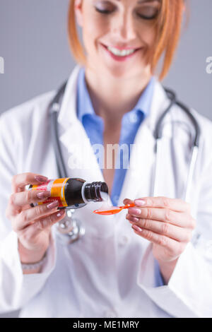 Die Hände der jungen Frau Doktor gießen Arzneimittel Sirup auf Löffel. Stockfoto