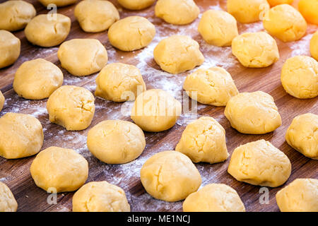 Eine Nahaufnahme der Käse Gebäck runde Brötchen vor dem Backen in geraden Reihen auf Mehl und einen hölzernen Tisch Stockfoto