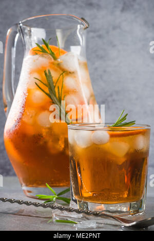 Eis kalten Tee in Krug und Glas mit Rosmarin garnieren. Stockfoto