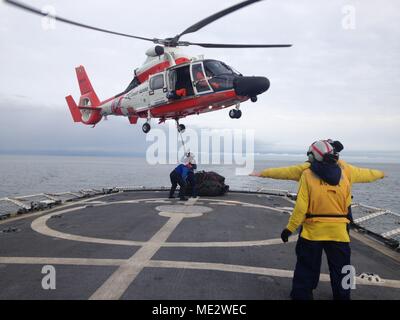 Besatzungsmitglieder an Bord der Coast Guard Cutter aktive Durchführung vertikaler Auffüllung Übungen mit einer flugzeugbesatzung an Bord eines MH-65D Dolphin Helikopter von Air Station North Bend, Erz, als Schnittobjekt Transite durch die Straße von Juan de Fuca, Washington, Dez. 21, 2017. Eine vertikale Nachschub wird eine Methode für die Bereitstellung von Verbrauchsmaterial, Zahnrad und Ausrüstung unterwegs Cutter per Hubschrauber. U.S. Coast Guard Foto von Ensign Ivonne Lassalle. Stockfoto