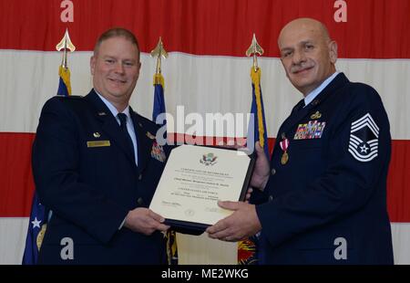 Oberst James DeVere, Kommandant der 302Nd Airlift Wing, stellt eine Bescheinigung über die Pensionierung zu Chief Master Sgt. James Smith, Betriebsleiter der 302Nd Instandhaltungsgruppe, während seiner Pensionierung Zeremonie im Hangar 210 an Peterson AFB, Colo., Dez. 2, 2017. Smith zieht sich nach 30 Jahren im Dienst der Luftwaffe - - von denen 20 waren für die Aufrechterhaltung der C-130 Herkules Flugzeug Flügel buchen. "Ich weiß, ich bin aus meiner Luftwaffe in große Hände", sagte Smith, zu denen seine Zeremonie teilnehmen. "Wegen Dir, weil Sie bereit sind, kann ich Ihnen sagen, dass ich mich getrost zurückziehen." (U.S. Air Fo Stockfoto