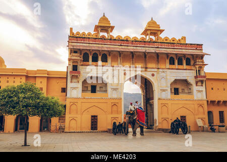 Dekoriert Elefanten mit Touristen ein Amer Fort Jaipur Rajasthan bei Sonnenaufgang. Amber Fort ist ein UNESCO-Weltkulturerbe. Stockfoto