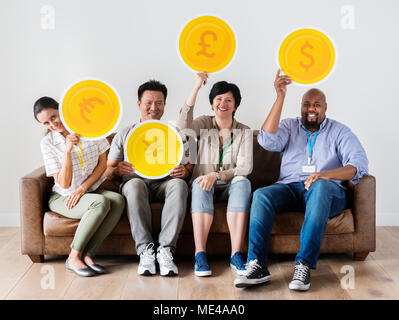 Diverse Arbeiter sitzen und halten Währung Symbole Stockfoto