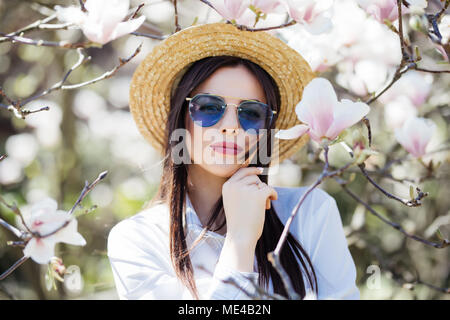 Schönheit Frau, die in der Nähe von Magnolia blühenden Blumen Baum im Frühjahr Graden Stockfoto