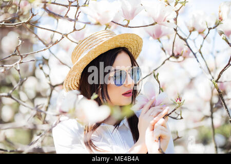 Schönheit Frau, die in der Nähe von Magnolia blühenden Blumen Baum im Frühjahr Graden Stockfoto