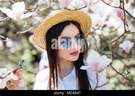 Schönheit Frau, die in der Nähe von Magnolia blühenden Blumen Baum im Frühjahr Graden Stockfoto