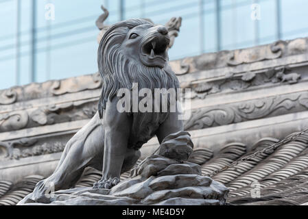 Lion Skulptur auf Daci buddhistischen Tempel Dach gegen moderne Gebäude in Chengdu, China Stockfoto