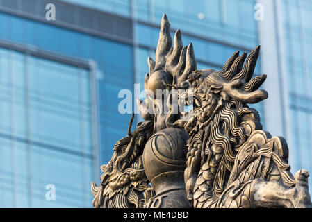 Dragon Skulptur auf Daci buddhistischen Tempel Dach gegen moderne Gebäude in Chengdu, China Stockfoto