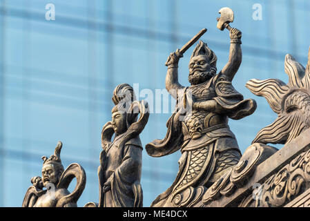 Dekoration Skulptur auf Daci buddhistischen Tempel Dach gegen moderne Gebäude in Chengdu, China Stockfoto