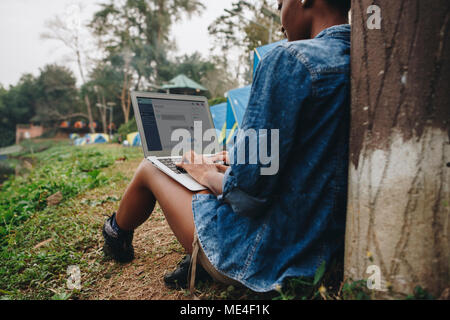 Frau alleine in der Natur mit einem Laptop auf einem Campingplatz Urlaub von der Arbeit oder von internetsucht Konzept Stockfoto