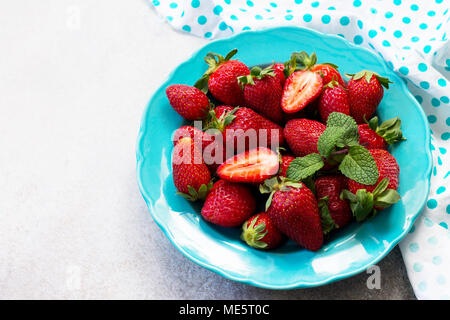 Beeren für frische Erdbeeren in einem blauen Keramikplatte auf grauem Stein oder Schiefer Hintergrund. Das Konzept der Ernährung Gesundheit oder Entgiftung. Stockfoto