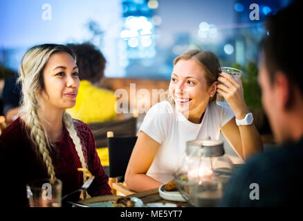 Freunde in ein gemeinsames Abendessen in eine Bar auf der Dachterrasse Stockfoto