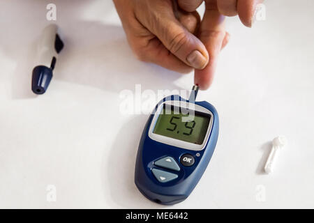 Medizin, Diabetes, Glykämie, Gesundheitswesen und Personen Konzept - Nahaufnahme der Frau Kontrolle der Blutzuckerspiegel durch glucometer und Test Streifen zu Hause. Noch Stockfoto