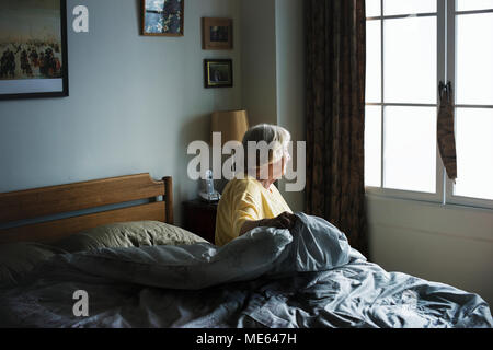 Ältere Frau sitzt in einem Schlafzimmer Stockfoto
