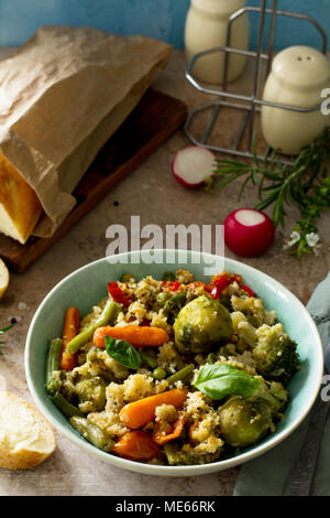 Gesunde Ernährung vegane Teller: Couscous und Gemüse (Bohnen, Rosenkohl, Karotten, Paprika, Tomaten) auf einem Stein oder Schiefer Hintergrund. Stockfoto