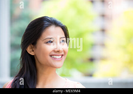 Closeup headshot Porträt, Lächeln, fröhliche, glückliche junge Frau auf der Suche nach Träumen, nette Sachen, isolierte Sonnig draussen, Gebäude Hintergrund. P Stockfoto