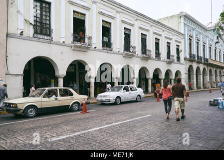 Die Menschen wandern, Parkplatz vor der alten Vintage White Gebäude in der Innenstadt von Merida, die Hauptstadt von Yucatan, Mexiko Stockfoto