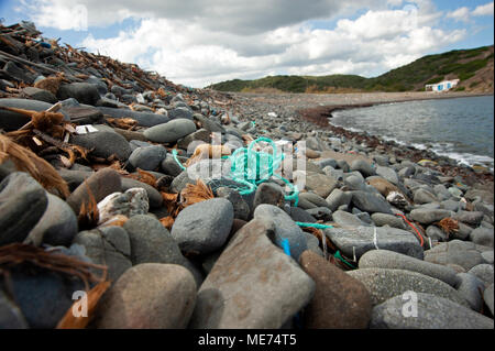 An einem Kiesstrand an der Nordküste der Insel Menorca, Spanien, werden Treibholz, Plastikmüll und Angelausrüstung gewaschen Stockfoto