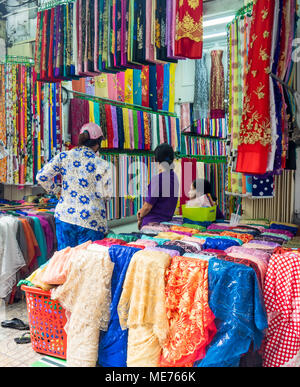 Eine Frau Einkaufen in einem Textilgeschäft mit bunten Stoffballen in einem Stoff Markt in Ho Chi Minh City, Vietnam. Stockfoto