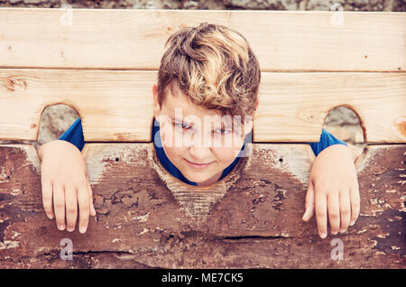 Jungen kaukasischen Jungen in mittelalterlichen Pranger. Elend Thema. Strafe Gerät. Rot Foto Filter. Stockfoto