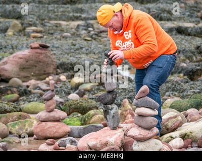 Dunbar, Schottland, 22. April 2018. Auge Cave Strand, Dunbar, East Lothian, Schottland, Vereinigtes Königreich, 22. April 2018. Der zweite Tag des zweiten Europäischen Stein stacking Meisterschaften an diesem Wochenende in Dunbar, von Dunbar Street Art Trail organisiert. Der erste Wettbewerb des Tages war die Anzahl der Steine in 20 Minuten. Der Gewinner ausgeglichen 29 Steine, etwas weniger als im letzten Jahr, gewann 32 Steine. Ein Konkurrent baut ein Stein Stapel Stockfoto