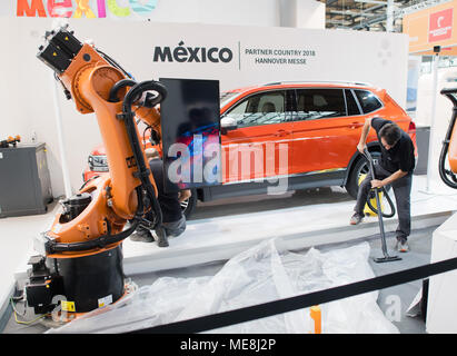 22 April 2018, Deutschland, Hannover: Arbeitnehmer machen letzte Vorbereitungen mit einem Volkswagen Tiguan und ein Kuka Roboter, auf dem Stand der Partner Land Mexiko auf der Hannover Messe Industrie- Messe. Foto: Julian Stratenschulte/dpa Stockfoto