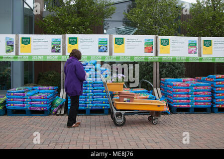 Frau, die Boden auswählt und Kompost anbauen in Southport, Merseyside, Großbritannien 22. April 2018. Wetter in Großbritannien. Gärtner strömen zu den Gartencentern, wenn das warme Wetter anhält, gedämpft mit leichten Duschen früher am Tag. Frühlingsbonanza für lokale Gartengeschäfte mit Einkäufern, die von ermäßigten Artikeln profitieren. Stockfoto