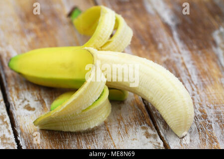 Die Hälfte geschält reife Banane auf Holzmöbeln im Landhausstil Oberfläche, Nahaufnahme Stockfoto