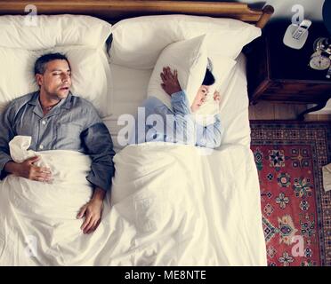 Interracial Paare auf dem Bett mann Schnarchen und Frau zu unterbrechen. Stockfoto