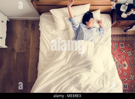 Asiatische Frau auf dem Bett Aufwachen am Morgen Stockfoto