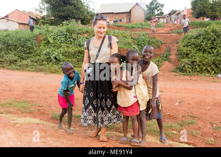 Lugazi, Uganda. 17. Mai 2017. Eine weiße Hautfarbe freiwillige ('mZungu' oder 'muzungu' lokal) Hände mit ugandischen Kinder in einer ländlichen Gegend. Stockfoto