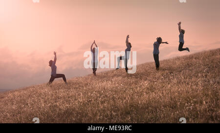 Gruppe von gleichen glücklich fröhliche Mädchen training Yoga Übung auf idyllischen Feld an schönen sonnigen Tag über den Wolken Stockfoto