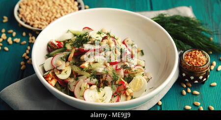 Salat mit Gemüse und Eier auf die bunten blauen Hintergrund. Close Up. Europäische Küche. Rettich, Gurke, Wachteleier und Pinienkernen. Ovo-vegetarisch Stockfoto