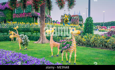 Baby Giraffen in einem Garten mit bunten Blumen Stockfoto