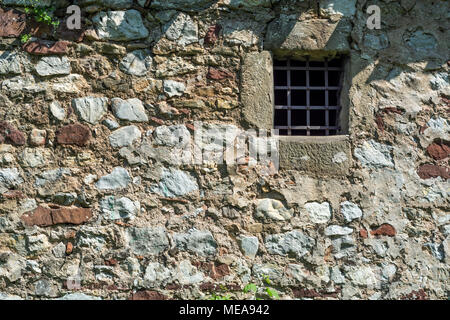 Altes, dunkles Alter Steinmauer und kleinen Gefängniszelle Fenster mit Bars Stockfoto