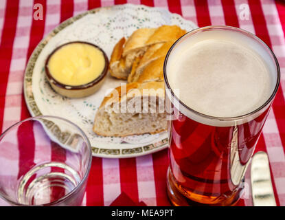 Typisch britischen Pub Mittagessen Erfrischung: ein Pint Bier in einer geraden-seitig Glas mit Brot und Butter auf einer rot-weiß karierten überprüft Tischdecke Stockfoto