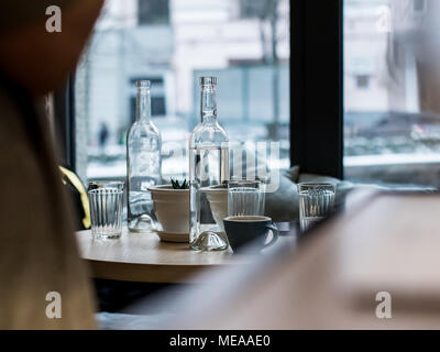 Im Cafe auf dem Tisch gibt es facettierte Gläser neben zwei durchsichtigen Flaschen, eines mit Wasser gefüllt. Auch auf dem Tisch ist eine Tasse und neben ihr ein Stockfoto