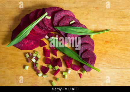 In Scheiben geschnittene Rübe mit grünen Blättern des wilden Knoblauch auf einer hölzernen Hintergrund der hellgelbe Farbe Stockfoto