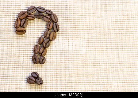 Kaffeebohnen sind in der Form eines Fragezeichens auf eine beige Serviette gelegt. Ein Symbol der Überraschung, Ignoranz. Stockfoto