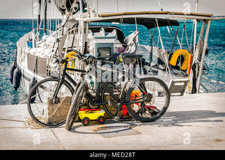 Fahrräder geparkt auf Jetty vor Segelboot. Stock Bild. Stockfoto