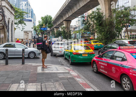 Ein Backpacker wartet auf ein leeres Taxi im dichten Verkehr auf der Sukhumvit Road, Bangkok, Thailand Stockfoto