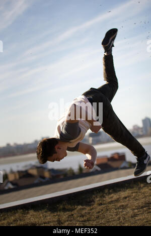 Junge männliche Sportler führt akrobatische Tricks springt vor der Skyline Stockfoto