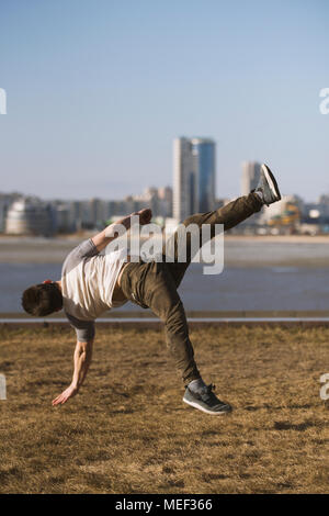 Junger Mann parkour Sportler führt akrobatische Sprünge vor der Skyline Stockfoto