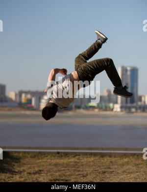 Junger Mann parkour Sportler führt zurück Tricks vor der Skyline Stockfoto