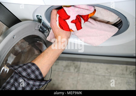 Mann nimmt die Dinge mit der Waschmaschine gewaschen. Stockfoto